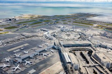 Aerial view of San Francisco International Airport showing aircraft, terminal gates, taxiways, and runways.